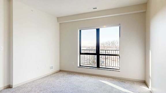 a bedroom with a window looking out to a balcony