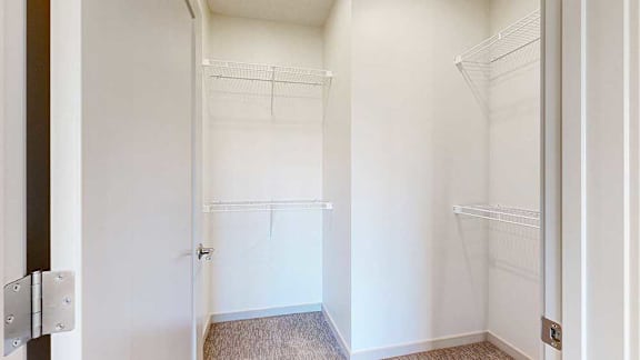 an L-shaped walk-in closet with built-in shelving
