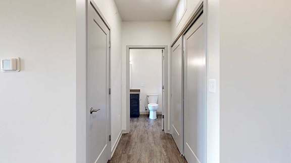 a hallway with two closets and an open door to a bathroom