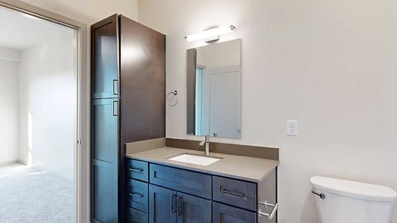 a bathroom with dark wooden cabinet and a quartz vanity sink