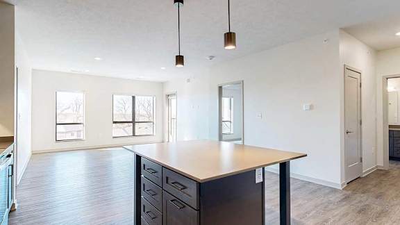 a kitchen table island with dark cabinets and quartz cabinets in front of a spacious living room