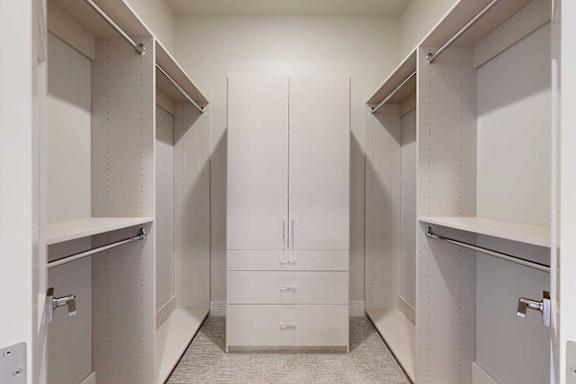 A boutique-style walk-in closet with built-in wooden shelving and hanging space as well as an armoire.