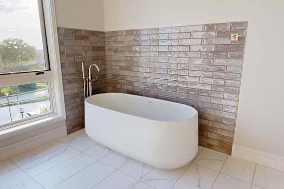 An oversized soaking tub in a bathroom with a tiled accent wall.