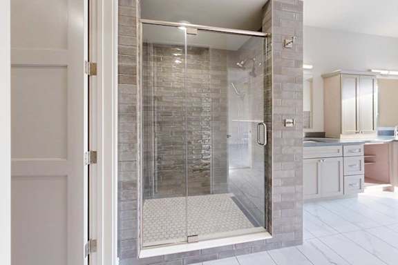 A modern bathroom with a tiled walk-in shower with a glass door.