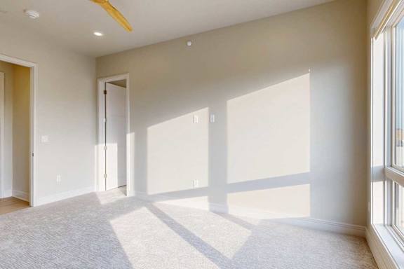 A bedroom with a 3-panel floor-to-ceiling window, a large ceiling fan, and an ensuite bathroom.