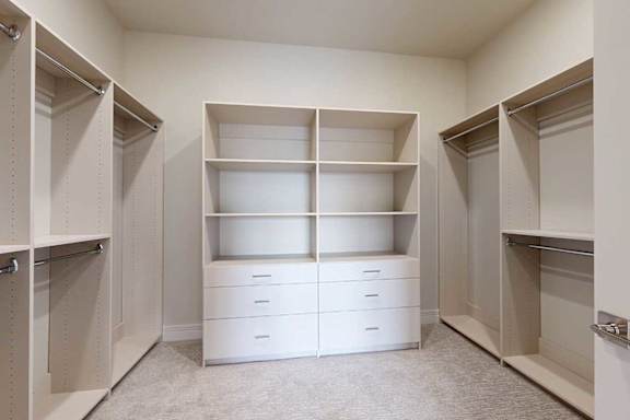 An oversized, boutique-style walk-in closet with built-in drawers and shelves.