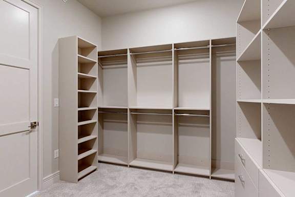 An oversized, boutique-style walk-in closet with built-in drawers and shelves.
