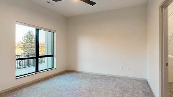 a bedroom with a large window and a ceiling fan