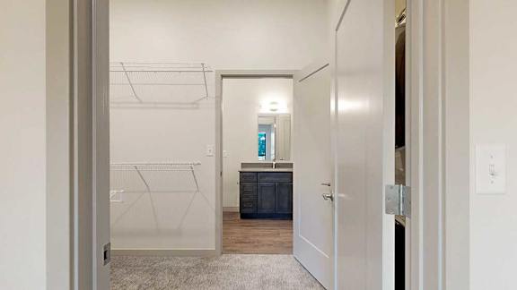 a walk-through closet with built-in shelving and a door to a bathroom