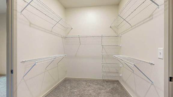a large walk-though closet with built-in wired shelving and hanging space