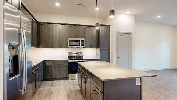 a modern kitchen with dark wood cabinets, stainless steel appliances, and quartz countertops