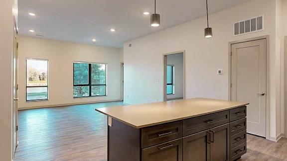 a spacious kitchen with a large island and wooden cabinets next to an open living room
