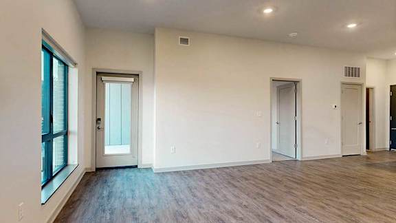 a living room with a door to the patio, a window, and a door to the bedroom