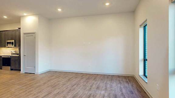 a spacious living room with wooden flooring and a kitchen to the left