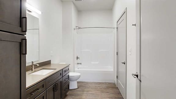 a bathroom with a wide vanity sink, a tall cabinet, and a shower