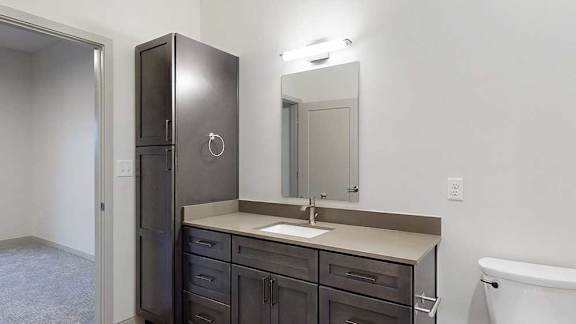 a bathroom with a sink, mirror, and tall storage cabinet