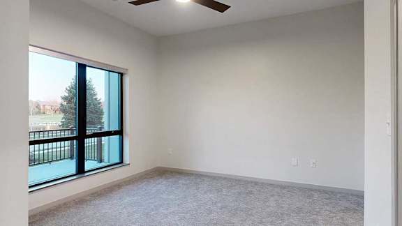 a bedroom with a large window and a ceiling fan