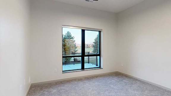 a bedroom with a large window overlooking a patio and trees