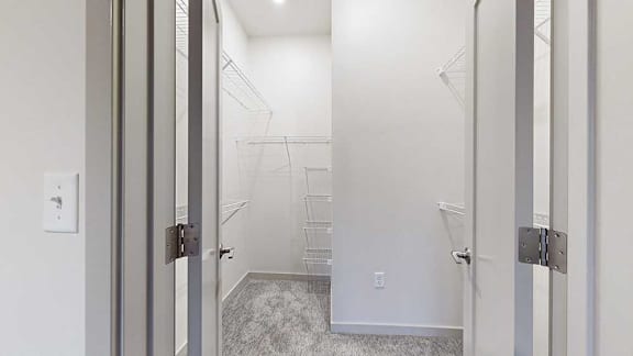 an L-shaped walk-in closet with build-in shelving and hanging space