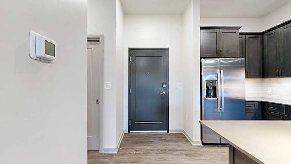 a modern kitchen with dark cabinets and a dark grey front door