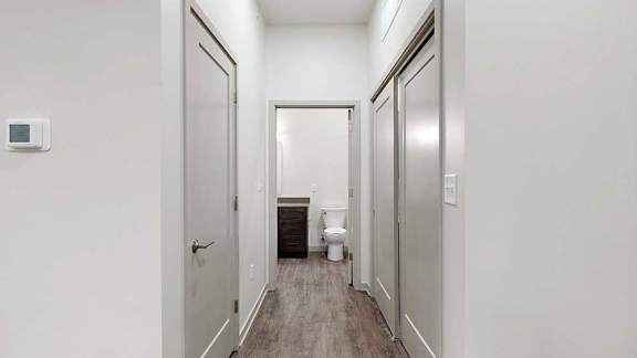 a hallway with a door open to the bathroom, a closed entryway closet, and closed laundry room
