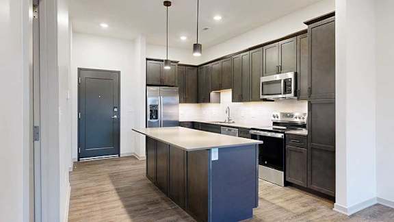 a modern kitchen with dark wood cabinets and a central island next to a front door