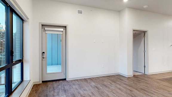 a living room with wooden flooring and a windowed door to a patio