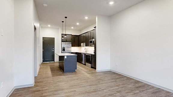 an open living room next to a kitchen with dark cabinets