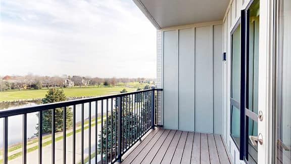 a balcony with a black metal railing and a view of the pond