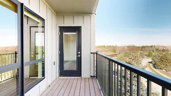 a balcony with a windowed door, a window to the bedroom, and a black railing
