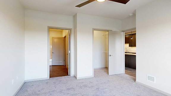a bedroom with carpeted flooring, a walk-in closet, and an attached bathroom