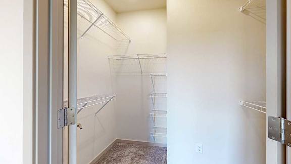 an L-shaped walk-in closet with built-in shelving and hanging space