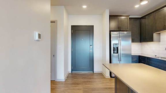 a kitchen with dark wood cabinets and stainless steel appliances next to a dark grey front door