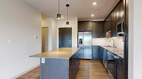 a modern kitchen with dark wood cabinets and stainless steel appliances next to a front door and a hallway