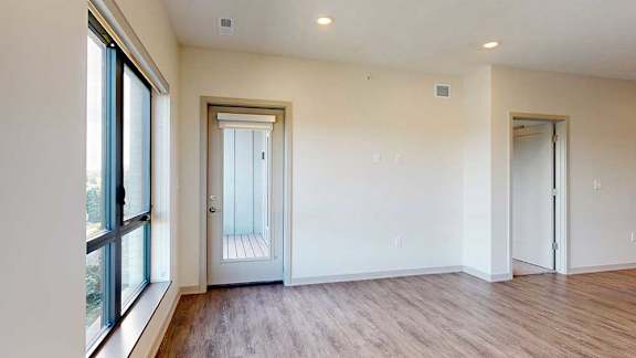 a living room with hardwood floors, a large window overlooking the pond, and a door to the balcony