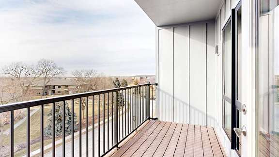 A balcony with a black metal railing and a view of the neighborhood.