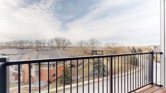 A balcony with a black metal railing and a view of the neighborhood.