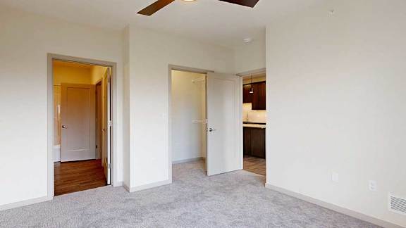 A bedroom with a ceiling fan, attached bathroom, and a walk-in closet.