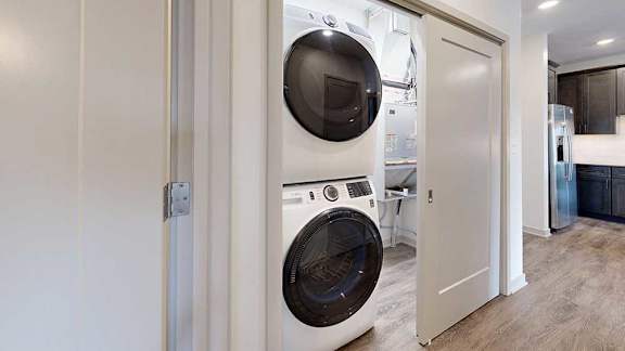 A stacked full-sized washer and dryer in a laundry room.