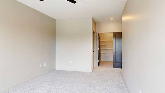 A bedroom with a ceiling fan, attached bathroom, and a walk-in closet.