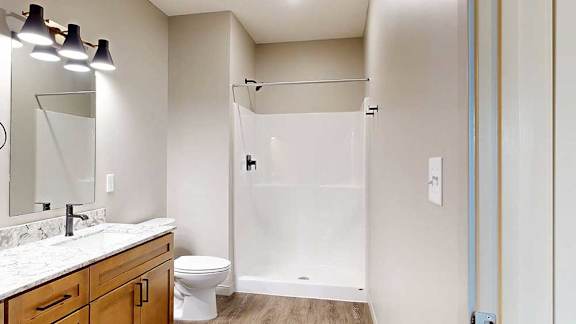 A bathroom with a walk-in shower with black fixtures.