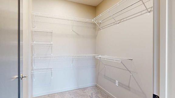 An oversized walk-in closet with several built-in wire shelves.