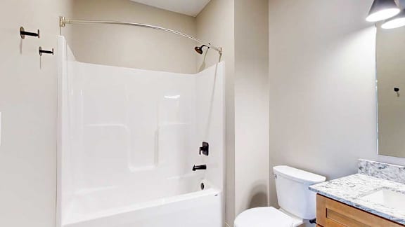 A bathroom with a white tub shower with black finishes, and a curved shower curtain rod.