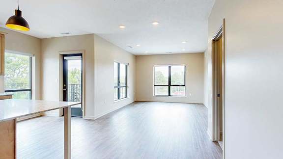 A living room with hardwood-style flooring and large floor-to-ceiling windows.