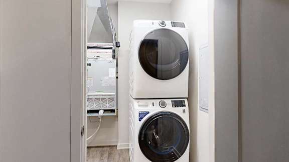 A stacked, full-sized washer and dryer in a laundry room.