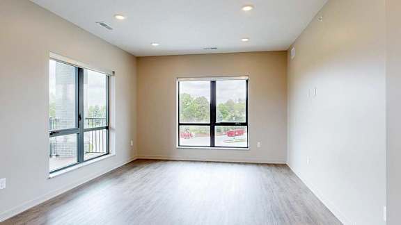 A living room with hardwood-style flooring and large floor-to-ceiling windows.