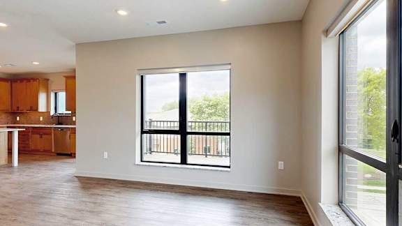 A living room with hardwood-style flooring and large floor-to-ceiling windows.