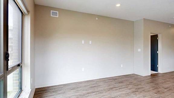 A living room with hardwood-style flooring and large floor-to-ceiling windows.