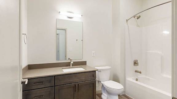a bathroom with a quartz vanity sink, a mirror, and a shower tub