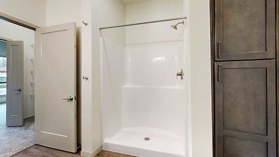 a bathroom with a walk-in shower next to a tall dark wooden storage cabinet